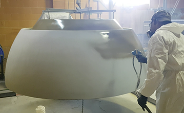 Manual spray painting of large, custom-made fiberglass light reflector in metal-based paint. Vacuum Metallizing Limited png